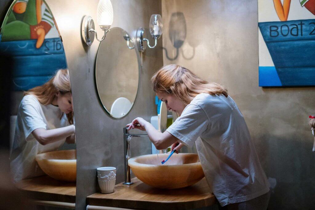 woman brushing her teeth in a bathroom with poor lighting